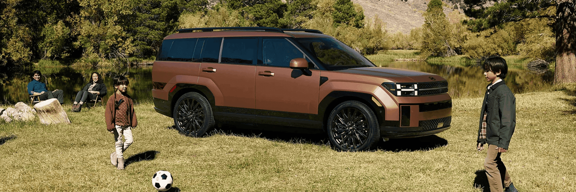 Brown 2026 Hyundai Santa Fe with kids playing soccer in the grass