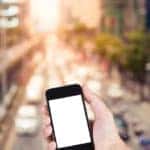 Person using smartphone white screen holder on hand with blurry of traffic jam on the city street